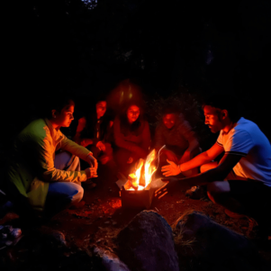 people around a bonfire at VanVaas, soil Village, Manali